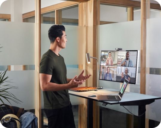 A professional man participates in a video conference call at a standing desk.
