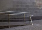 Stainless-steel handrails beside a short ramp and steps at an entrance
