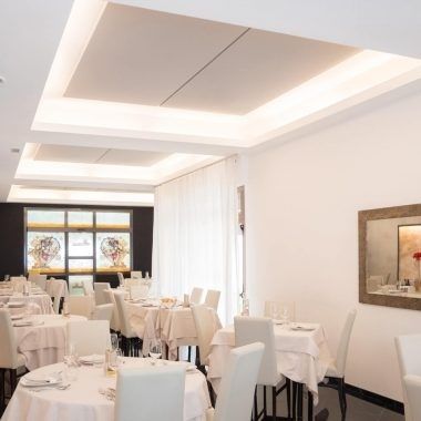 Bright restaurant dining room with high ceilings and white table settings