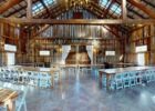 Rustic barn event hall with high ceiling, wood walls, and folding tables