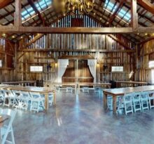 Rustic barn event hall with high ceiling, wood walls, and folding tables