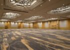 Empty hotel ballroom with patterned carpet and ornate chandeliers