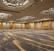 Empty hotel ballroom with patterned carpet and ornate chandeliers
