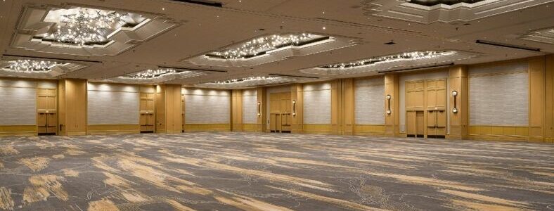 Empty hotel ballroom with patterned carpet and ornate chandeliers